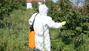 Man in protective body suit spraying pesticides